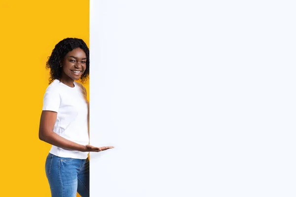 Mulher negra atraente mostrando placa de publicidade em branco — Fotografia de Stock