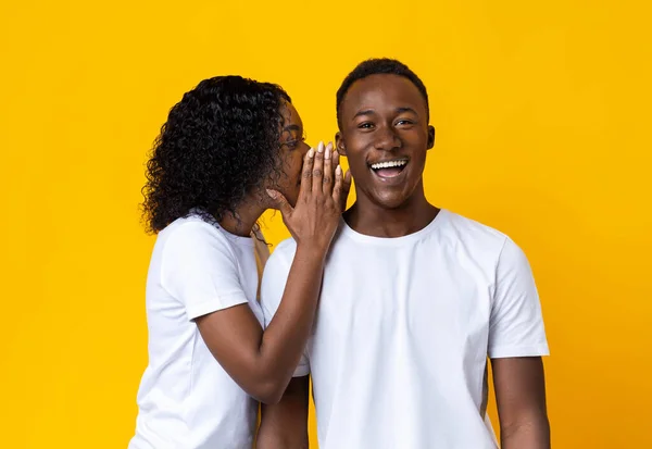 African american woman whispering something to her amazed boyfriend