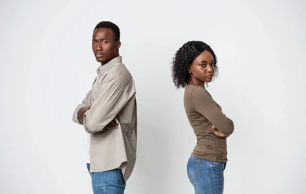 Upset black couple standing back to back on gray background — Stock Photo, Image