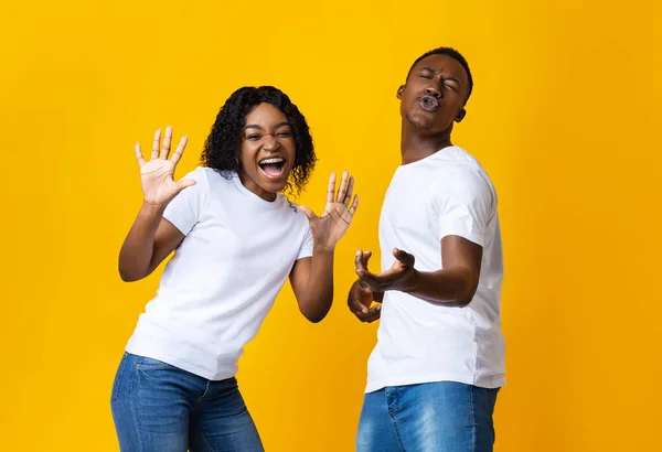 Homem negro emocional e mulher dançando e cantando em amarelo — Fotografia de Stock