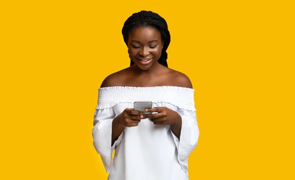Интересное приложение. Портрет счастливой чернокожей леди на желтом фоне — стоковое фото