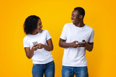 Neşeli genç adam ve kadın akıllı telefonlarda birlikte oynuyorlar.