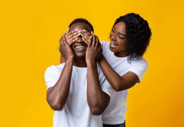 Beautiful black woman covering man eyes, preparing surprise