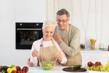 Son sınıf çifti mutfakta akşam yemeği için salata yapıyor.