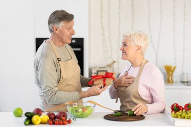 Yaşlı koca, evdeki mutfakta karısına hediye veriyor.