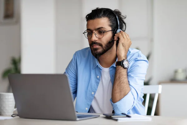 Enfocado chico indio en auriculares viendo webinar en el ordenador portátil en casa — Foto de Stock