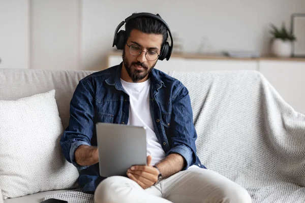 Ragazzo indiano trascorrere del tempo a casa con tablet digitale e cuffie wireless — Foto Stock