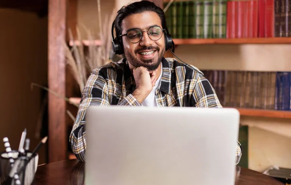 Estudiante Guy viendo video conferencia en línea en el ordenador portátil sentado en interiores —  Fotos de Stock