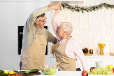 Olgun çift mutfakta dans ediyor, Noel 'de yemek pişiriyor.