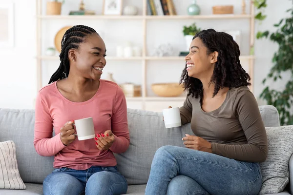 Feliz negro novias disfrutando fin de semana juntos, beber café en sofá — Foto de Stock