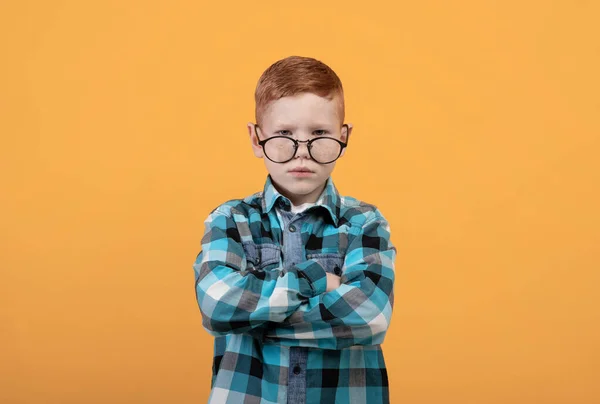 Niño enojado en gafas con los brazos cruzados en amarillo — Foto de Stock