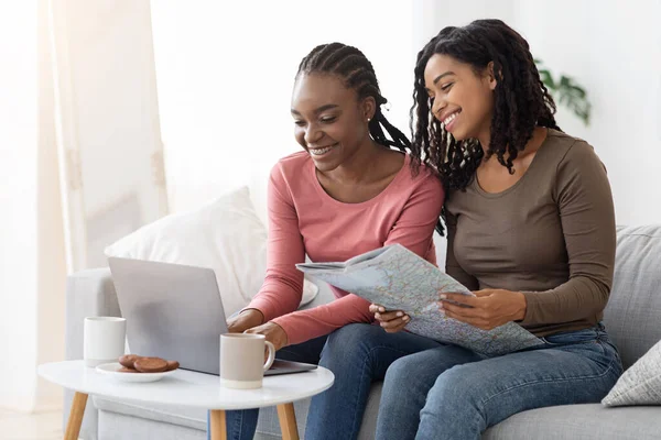 Two cheerful black women checking hotels online, using laptop — ストック写真