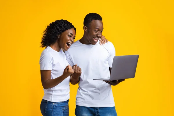 Couple noir positif célébrant victoire avec ordinateur portable — Photo