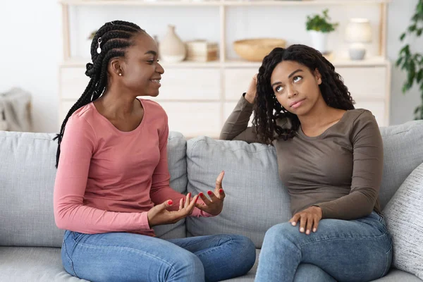 Dishonest african american woman listening to her happy girlfriend — Stock Photo, Image