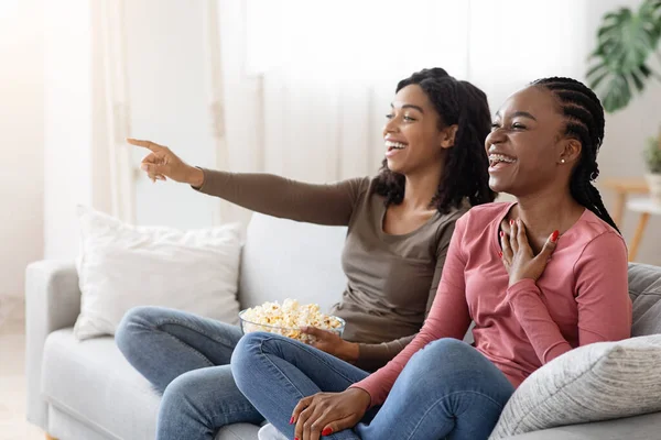 Två svarta flickvänner som har kul hemma, tittar på komedi — Stockfoto