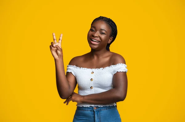 Alegre preto mulher mostrando paz gestos enquanto posando sobre amarelo fundo — Fotografia de Stock