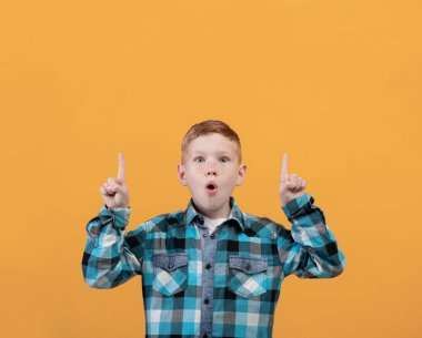 Shocked kid showing exciting advertisement, aiming at free space