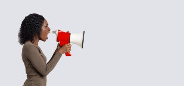 Gri arka planda megafonla bağıran genç siyahi kadın.