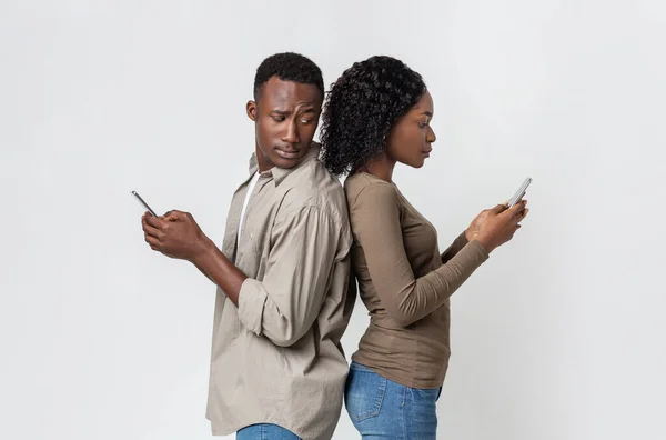Afrikaanse man en vrouw staan rug aan rug, met behulp van smartphones — Stockfoto