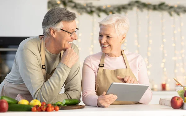 Senior pár s tabletovým počítačem Příprava vánoční večeře v kuchyni — Stock fotografie