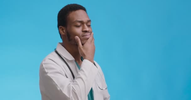 Studio portrait of thoughtful african american doctor thinking over hard medical case, blue background — Stock Video