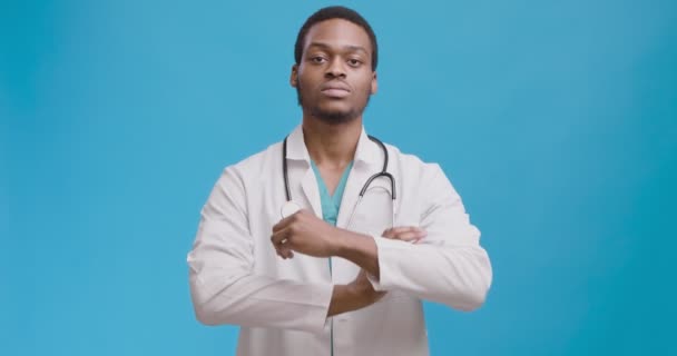 Retrato de estudio de un médico afroamericano serio y confiado cruzando los brazos y asintiendo a la cámara — Vídeos de Stock