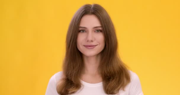 Mladá hravá dáma mrkání a úsměv na kameru, zavřít studio portrét přes oranžové studio pozadí — Stock video