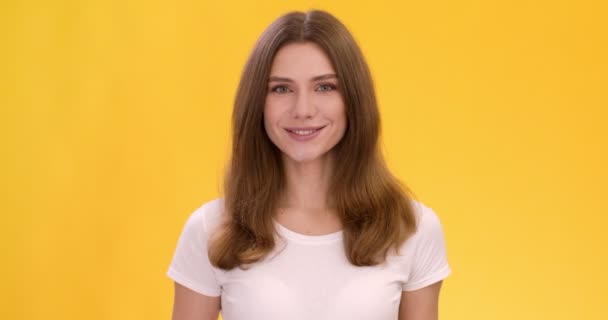 Estudio retrato de joven linda mujer caucásica sonriendo sobre fondo naranja — Vídeo de stock