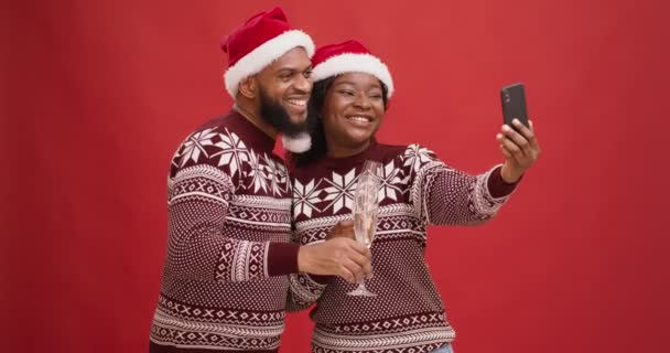 Weihnachtsfeier auf Distanz. Glückliches afrikanisch-amerikanisches Paar mit Champagner im Gespräch mit Freunden im Videochat — Stockvideo