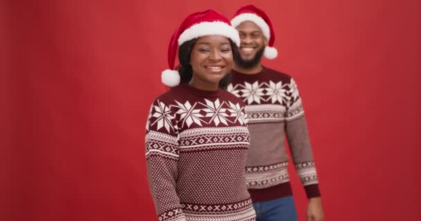 Giovane uomo afro-americano che viene alla sua ragazza e chiude gli occhi, giocando gioco di Natale peekaboo, sfondo rosso — Video Stock