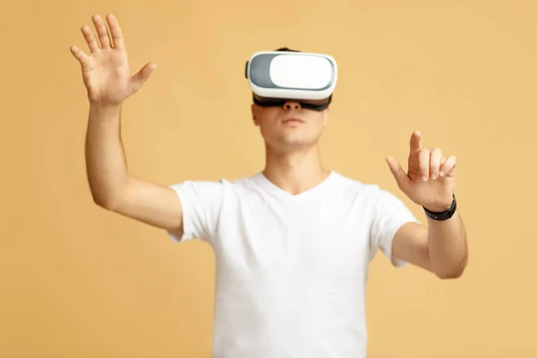 Busy young male student in white t-shirt and virtual reality glasses controlling gestures — Stock Photo, Image