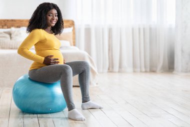 Gülümseyen hamile kadın spor salonunda egzersiz yapıyor.