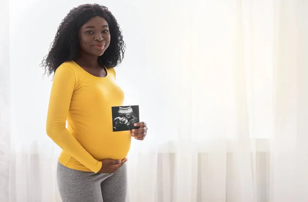 Щаслива вагітна чорна жінка показує свою дитячу сонографію — стокове фото