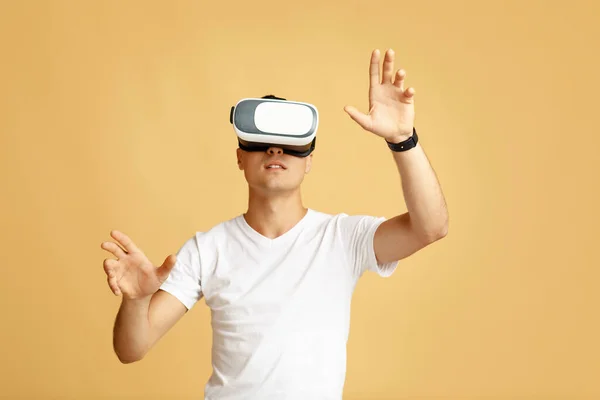 Surprised young male student in white t-shirt and vr spectacle moves hands, manipulating gestures — Stock Photo, Image