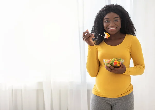 Feliz madre embarazada negro mujer comer fresco ensalada en casa — Foto de Stock