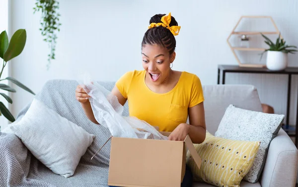 Aufgeregte schwarze Frau packt nach Online-Einkauf Schachtel aus — Stockfoto