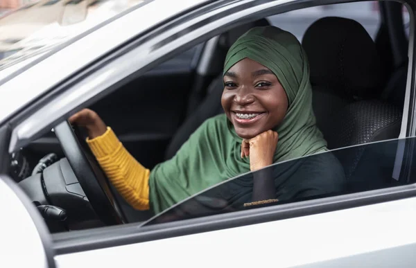 Gelukkig zwart religieus vrouw in hidjab poseren van chauffeurs stoel in auto — Stockfoto