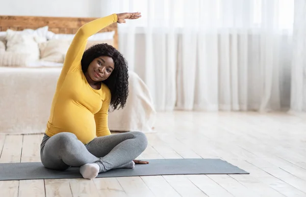 Alegre mujer embarazada negra haciendo ejercicios matutinos en casa — Foto de Stock