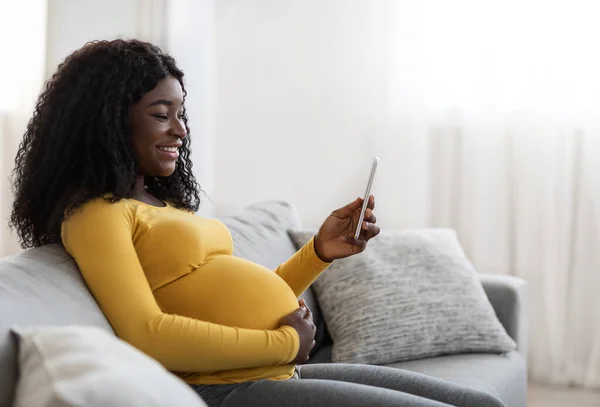 Feliz mujer embarazada negro sosteniendo el teléfono móvil — Foto de Stock