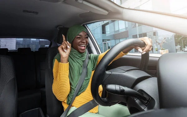 Happy moslim zwart vrouwelijke bestuurder zingen en dansen tijdens het rijden auto — Stockfoto