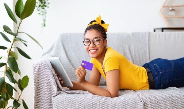 Mujer negra usando tableta y tarjeta de crédito en el sofá — Foto de Stock