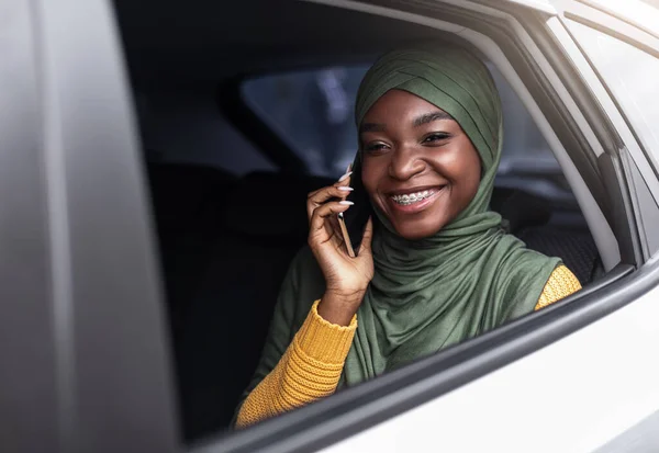 Zwarte moslim dame reist met de auto op de achterbank en praten op mobiele telefoon — Stockfoto