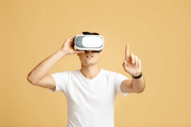VR gözlüklü bir adam sanal gerçeklik kulaklığıyla bir şeye parmak ile dokunmaya çalışıyor.