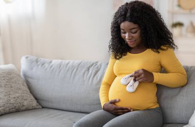 Mutlu Afrikalı bir kadının bebek ayakkabılarıyla oynamasını bekliyor.