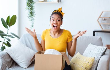 Excited black woman unpacking box spreading hands