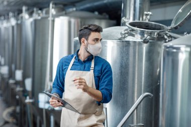 Factory employee works with equipment for industrial beer production