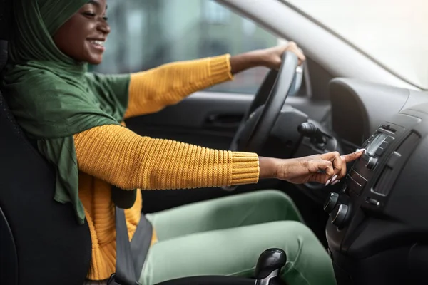 Positieve zwarte religieuze dame in hijab luisteren radio in auto, van kanaal veranderen — Stockfoto