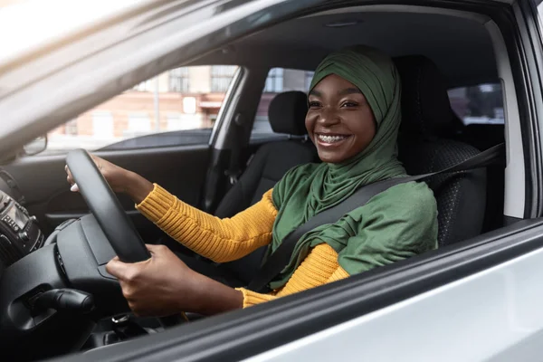 Een reisje. Zwarte moslim vrouw in hidjab genieten van bestuurder auto in de stad — Stockfoto