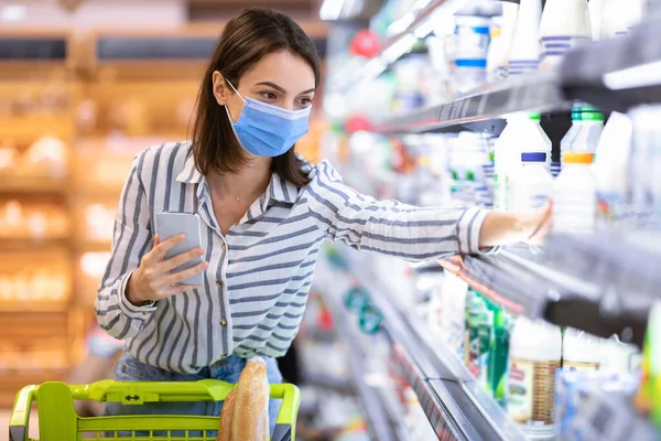 Süpermarkette alışveriş yapan maskeli bir kadın.
