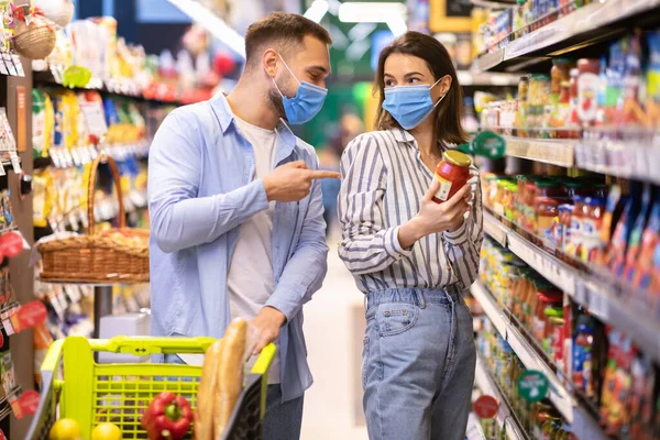 Young couple in masks shopping in supermarket — Stock Photo, Image